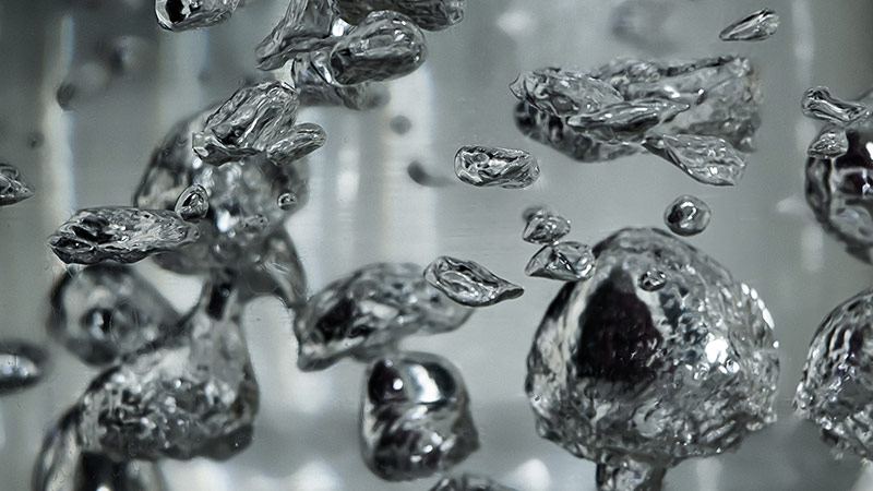 Close-up of drops and bubbles of mercury in water.