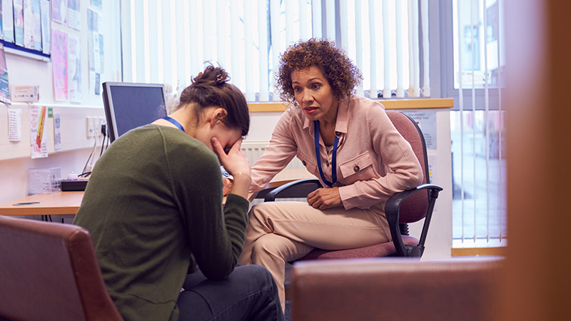 Female college student sharing her mental health issues with a campus counsellor.