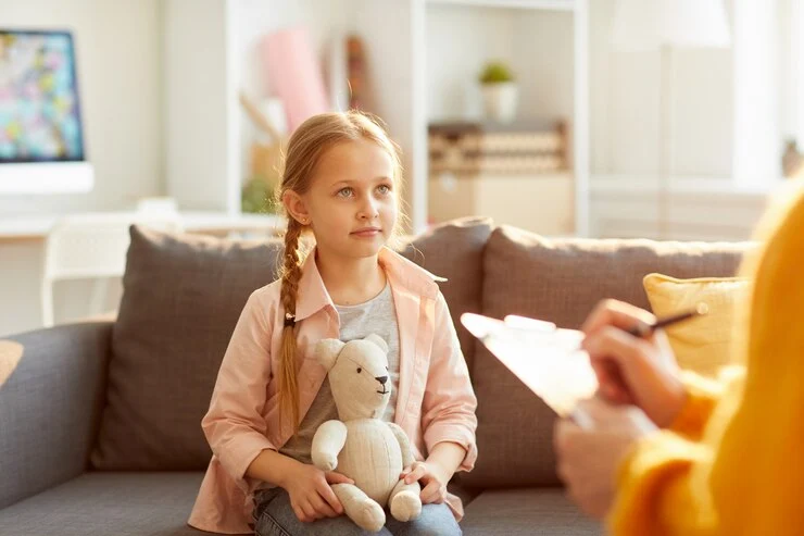 Cute little girl intently listening to her therapist during therapy session.