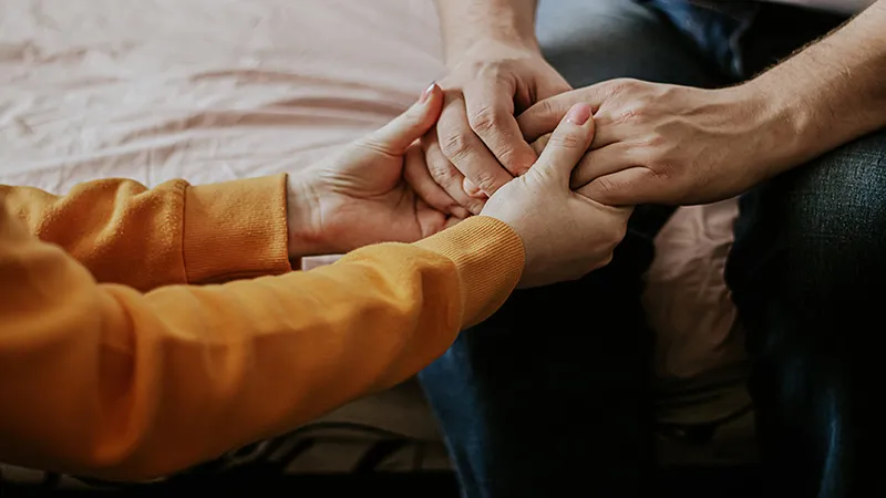 A young man holding hands of an elderly