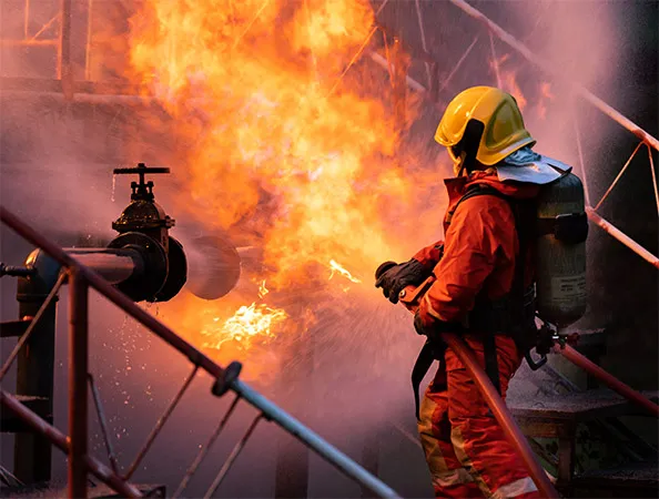 A firefighter uses a water fog-type fire extinguisher to extinguish the flames from an oil pipeline leak