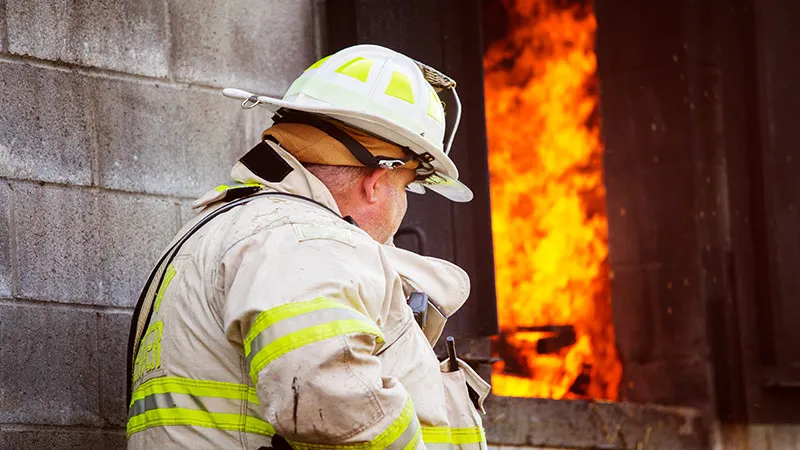 Firefighter standing in wall and observes fire 