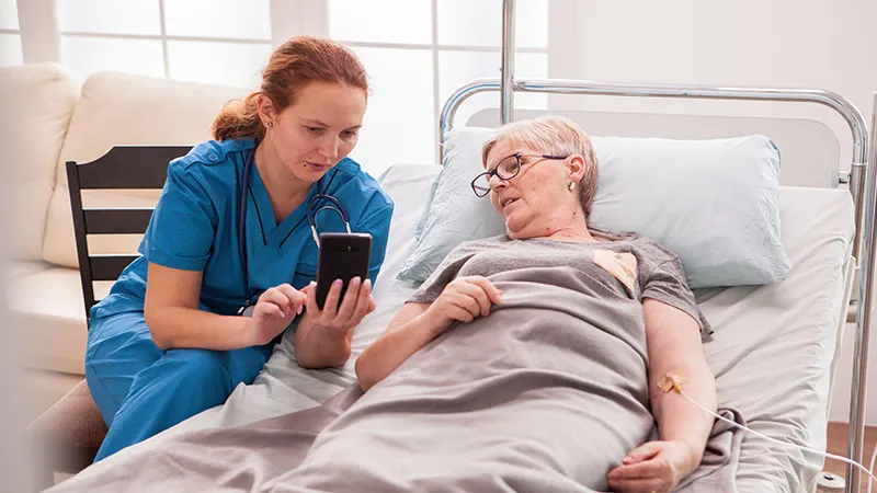 Nurse helps a senior woman in a hospital bed