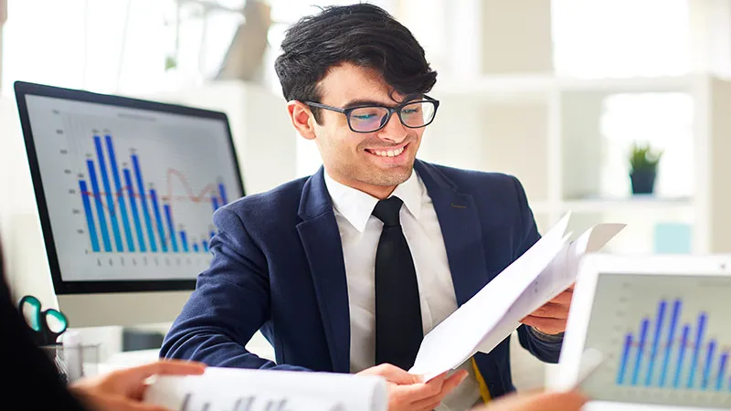 A smiling male accountant shows documents in his office