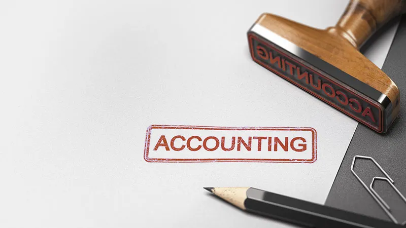 A rubber stamp and the word accounting on a sheet of paper with the idea of accountant 