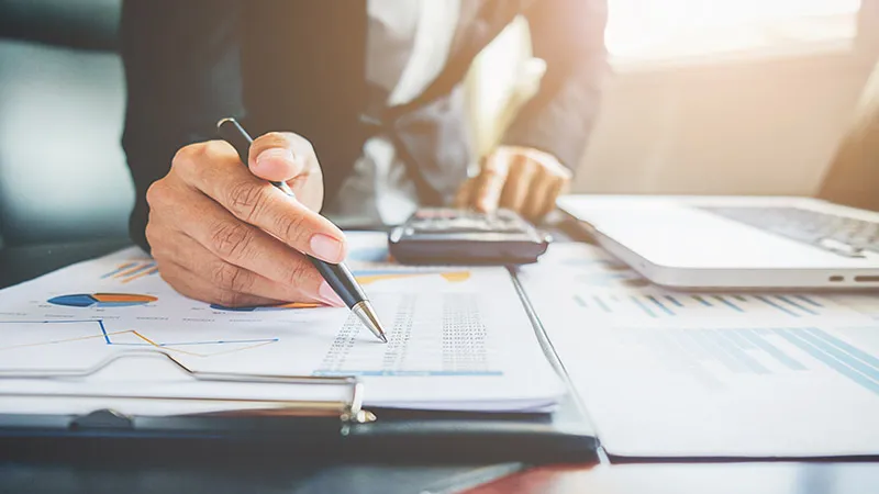 An accountant checks financial transition on paper with calculator or pen