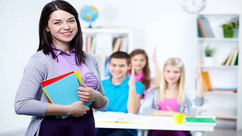 A happy primary teacher with students background