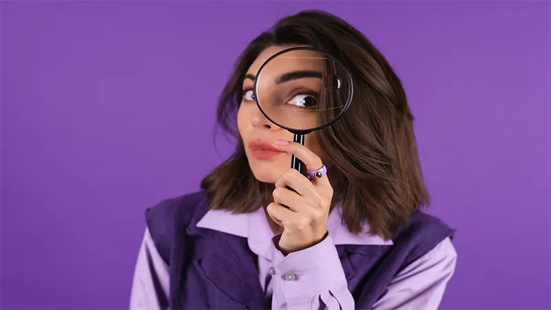 A female detective holds magnifying glass