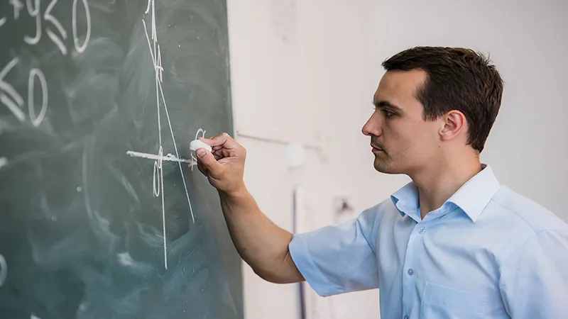Young teacher drawing a triangle on a blackboard with a formula