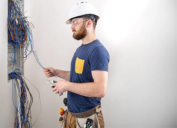 An electrician examines the cable connection in the electrical line