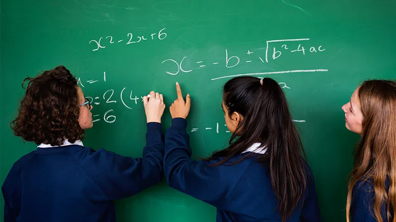 Three female students solve math problems in blackboard 