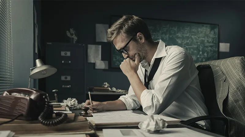A male mathematician sits at his desk and study