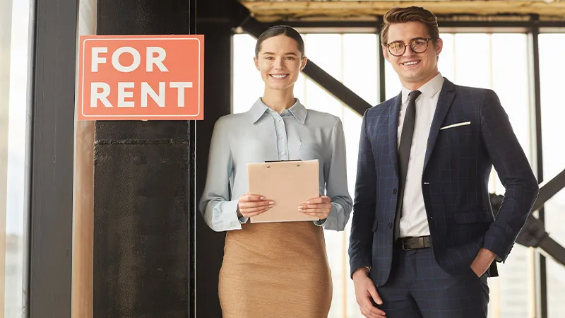 Man and woman standing in front of For rent board 