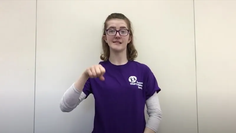 Woman teaching how to sign Yes in BSL with her right hand