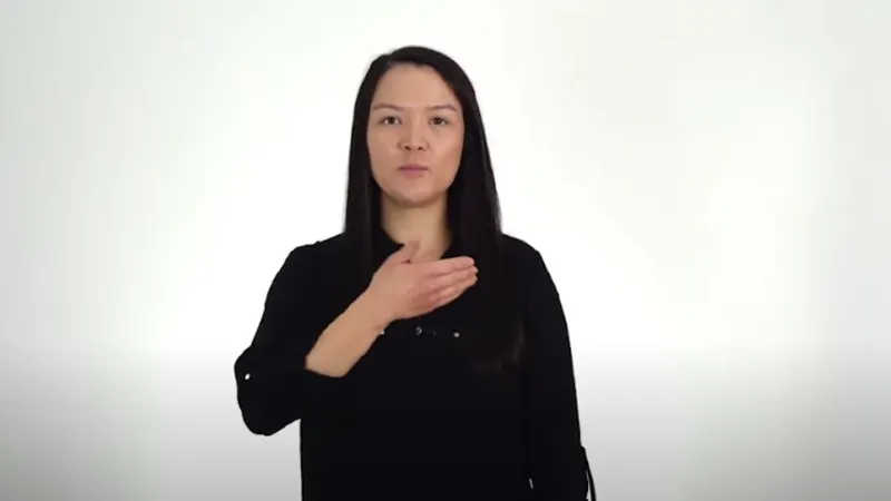Sign language interpreter with one hand in front of her mouth