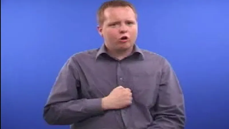 Man sitting on a chair while his right hand near his chest in a fist, trying to say something