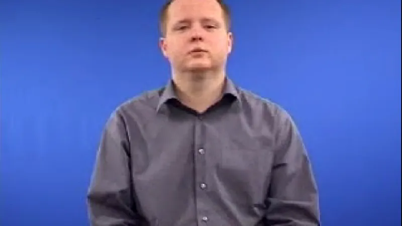 Sign language tutor seated in a room with blue background