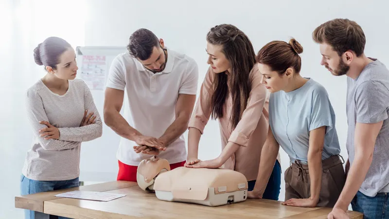Instructor teaching how to perform CPR on a dummy