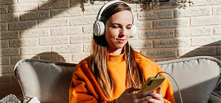  A woman earring headphones and listening to spanish podcast