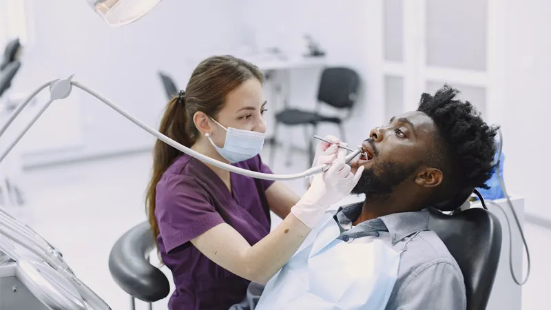 Female dentist examining the teeth of her client