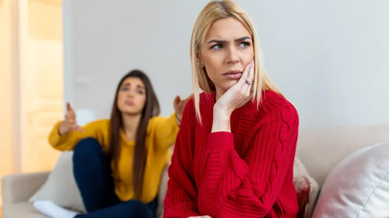 A woman wearing a red sweater is upset and her friend is confused why