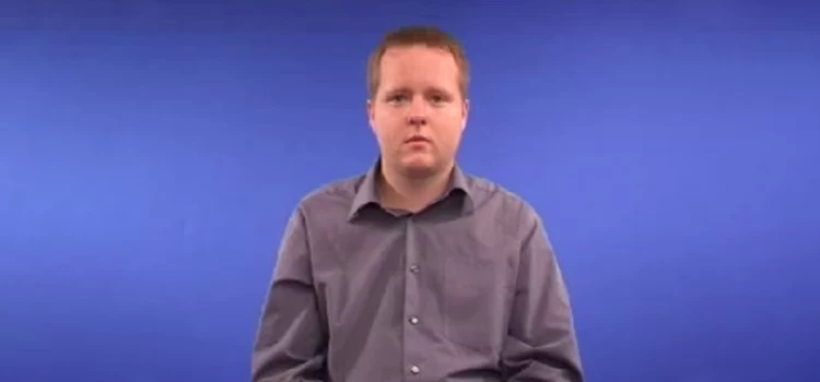 Male instructor seated with a normal posture in a blue background room