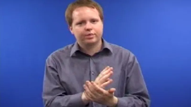 Man seated in his room with his right hand placed vertically on his left palm