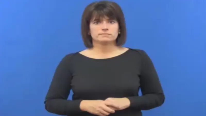Female BSL tutor standing straight with the arms placed near the stomach