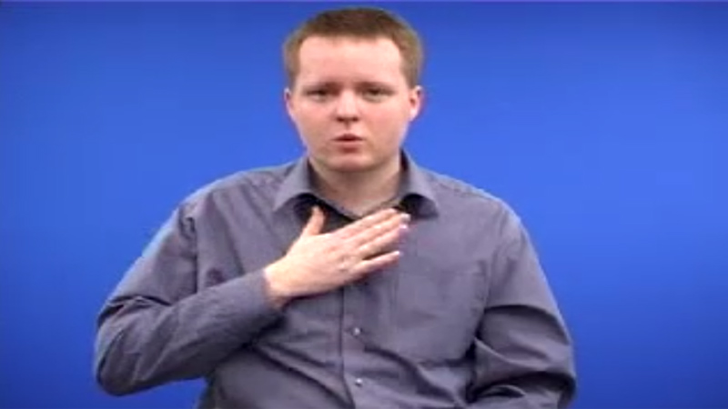 BSL Interpreter holding his right hand close to his chest