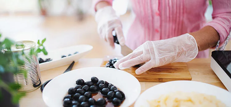 A woman wear gloves while chopping in kitchen