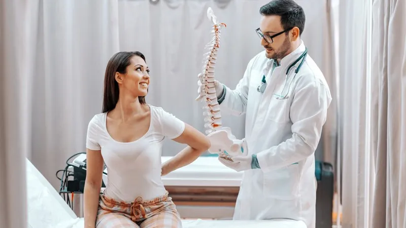 A chiropractor showing artificial spine to her patient