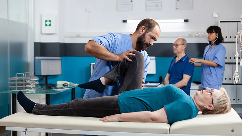 A chiropractic specialist helping aged woman with her leg