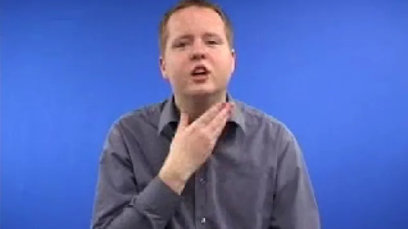 BSL instructor seated with his hand near his neck