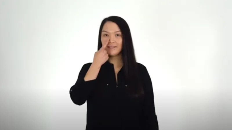 BSL interpreter touching her nose