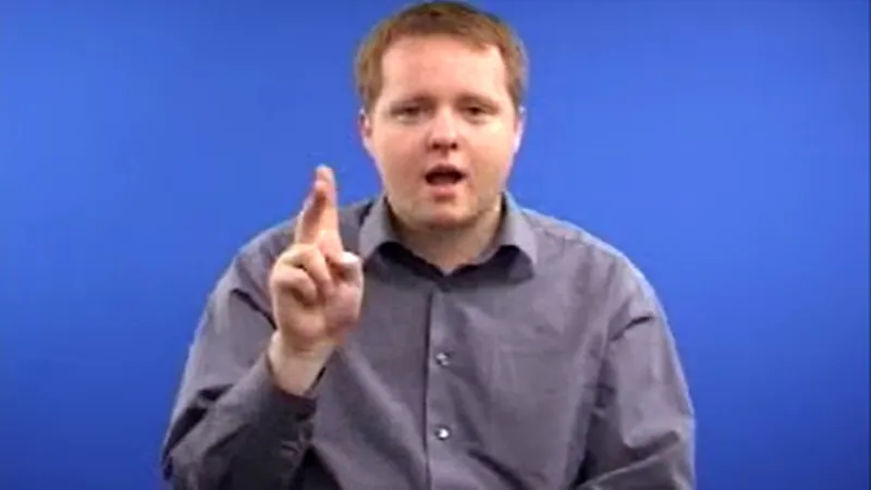 A man shows how to sign “Cool” in British sign language