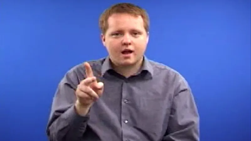 A man shows how to sign “Cool” in British sign language