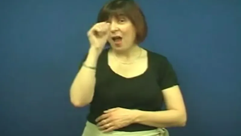 A woman shows the British Sign Language sign for "flower." 