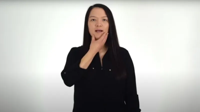 BSL interpreter holding her chin with one hand