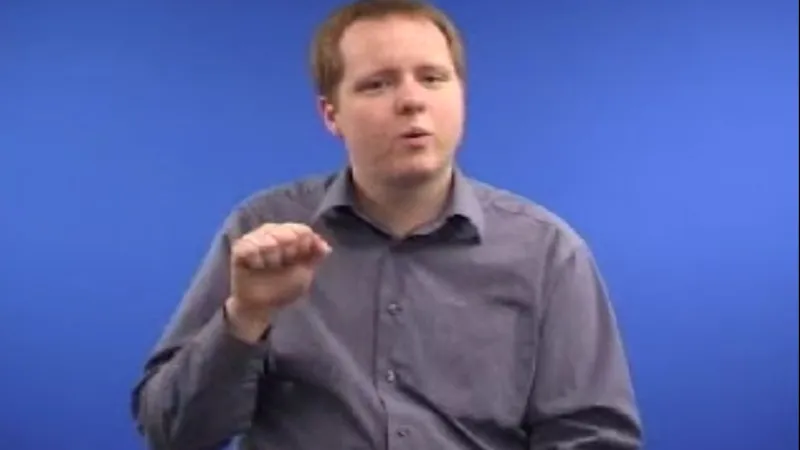BSL interpreter with right hand folded in a fist 