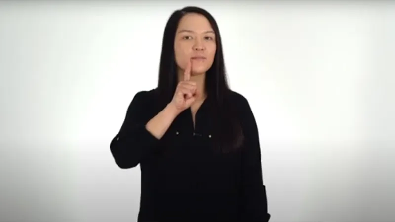 BSL tutor with index finger near her lips