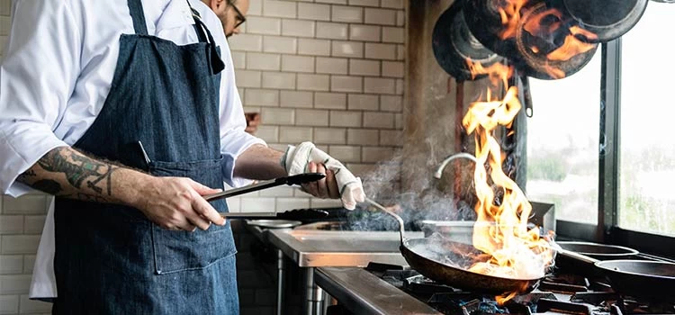 A male chef cooking food at restaurant kitchen