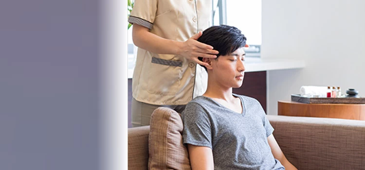 A man taking head massage from a woman masseuse