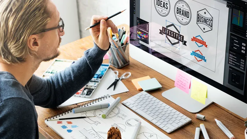 A man designing logo and eating cookie 