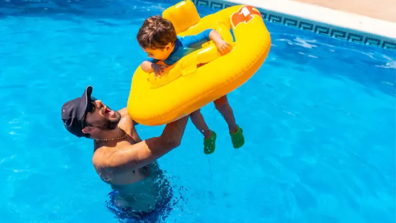A man in the swimming pool with his son