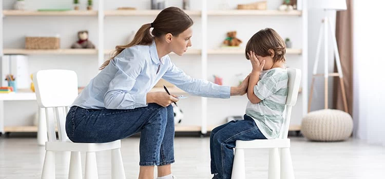 Upset little boy in psychologist's office unable to control his emotions while sharing his problems with psychologist.