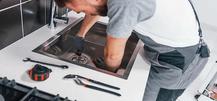 A residential plumber fixing kitchen sink
