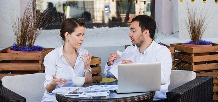  A young man and woman in formal attire having a serious conversation at a coffee shop. 