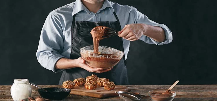 Chef using rotary egg beater for mixing cake batter