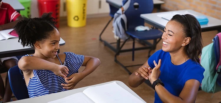 Little girl using british sign language to communicate with the teacher