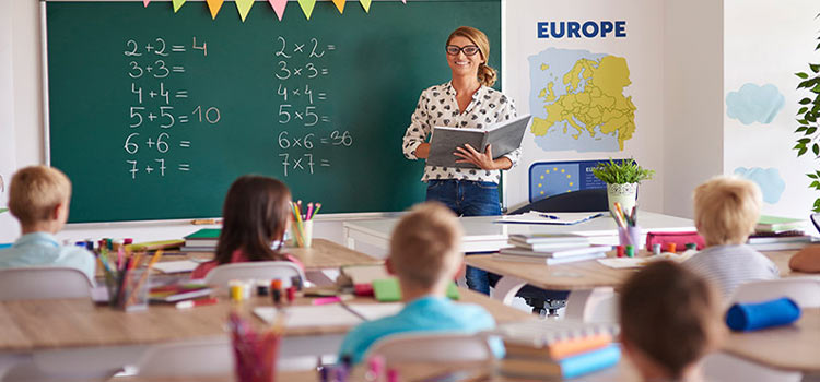 Female teacher cheerfully delivering lectures to a bunch of kids in the classroom.